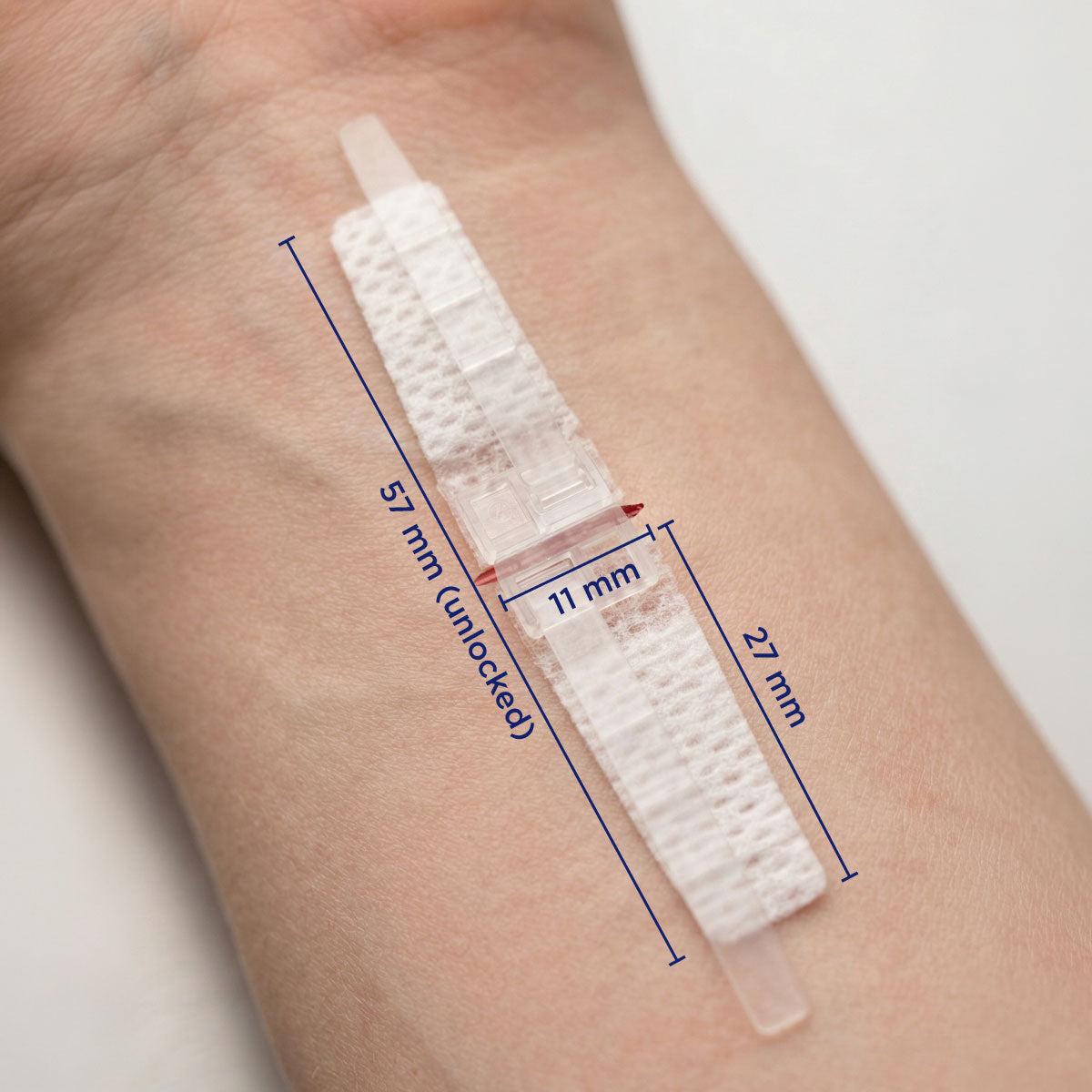 DermaClip Regular single clip applied to wrist showing 11mm clip width, 27mm pad length, 57mm total device length